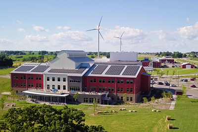 Organic Valley headquarters is seen with solar panels on its roof and wind turbines in the background.