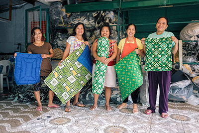 Image includes five women owners of a worker co-op posing with their products.